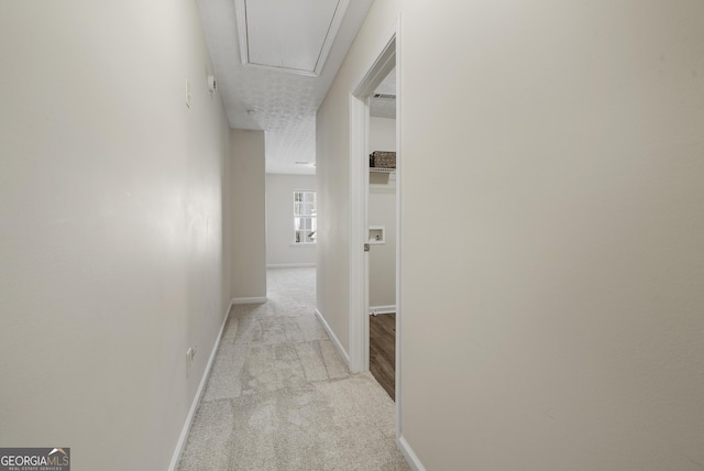 hallway with carpet floors, attic access, and baseboards