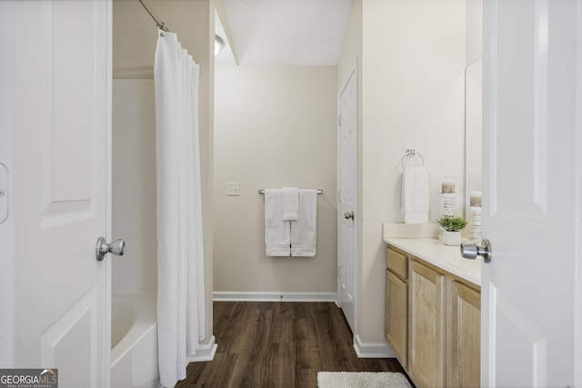 full bath featuring shower / bath combo, vanity, baseboards, and wood finished floors