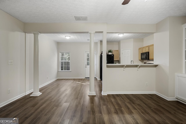 kitchen featuring black microwave, decorative columns, dark wood-style floors, and visible vents