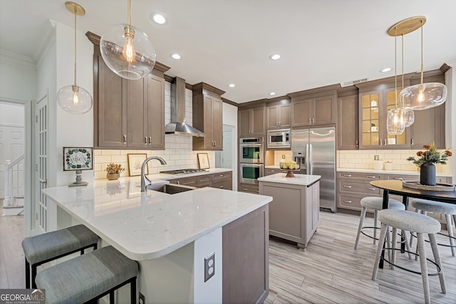 kitchen with stainless steel appliances, visible vents, a kitchen island, a peninsula, and wall chimney exhaust hood