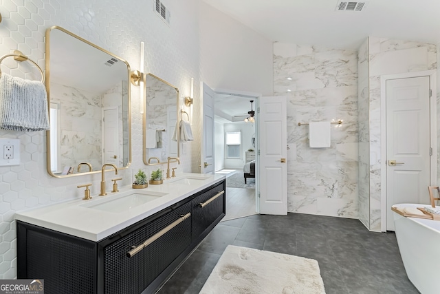 bathroom with double vanity, visible vents, vaulted ceiling, a freestanding tub, and a sink