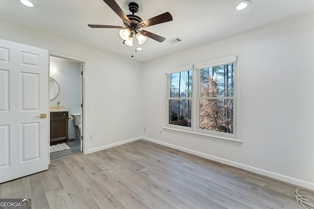 unfurnished bedroom featuring light wood finished floors, baseboards, visible vents, ensuite bath, and recessed lighting