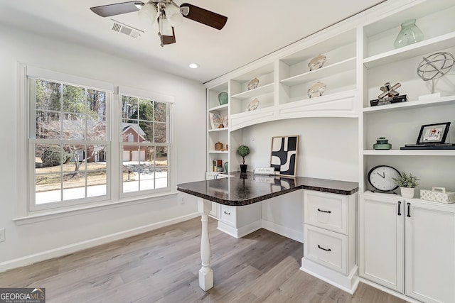 office area featuring light wood-style flooring, built in desk, visible vents, and a healthy amount of sunlight