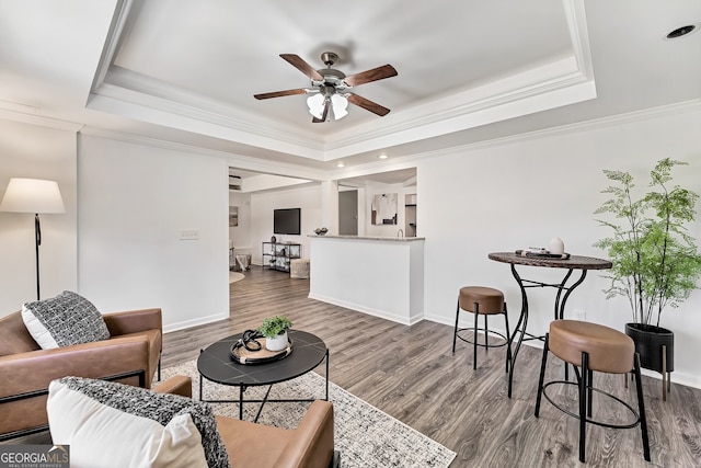 living room with a tray ceiling, wood finished floors, and baseboards