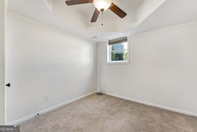 spare room featuring ceiling fan, carpet floors, baseboards, ornamental molding, and a raised ceiling