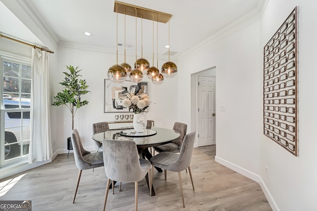 dining space with light wood finished floors, ornamental molding, and baseboards