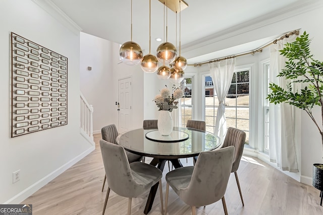 dining room with light wood-type flooring, baseboards, stairway, and crown molding