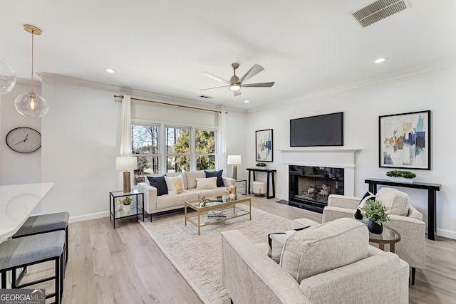 living area with light wood finished floors, baseboards, a premium fireplace, and visible vents