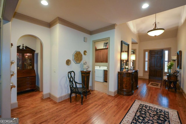 entrance foyer featuring washer / dryer, ornamental molding, baseboards, and wood finished floors