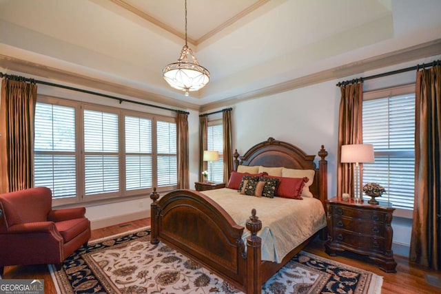 bedroom with a tray ceiling, wood finished floors, and crown molding