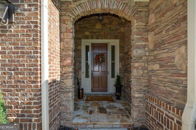 view of exterior entry featuring stone siding and brick siding