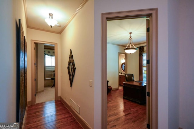 hall featuring baseboards, visible vents, ornamental molding, and dark wood-type flooring