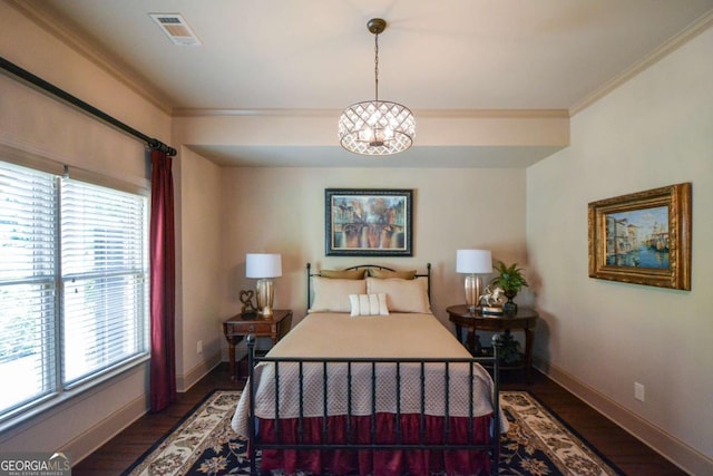 bedroom with ornamental molding, visible vents, baseboards, and wood finished floors