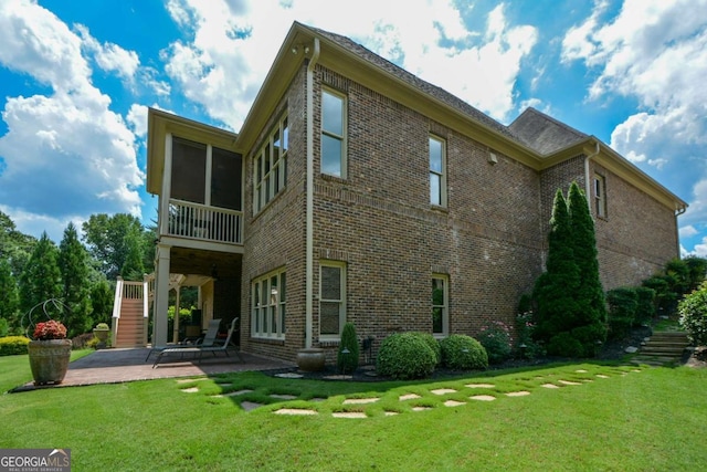 rear view of house with a yard, a patio, brick siding, and stairway