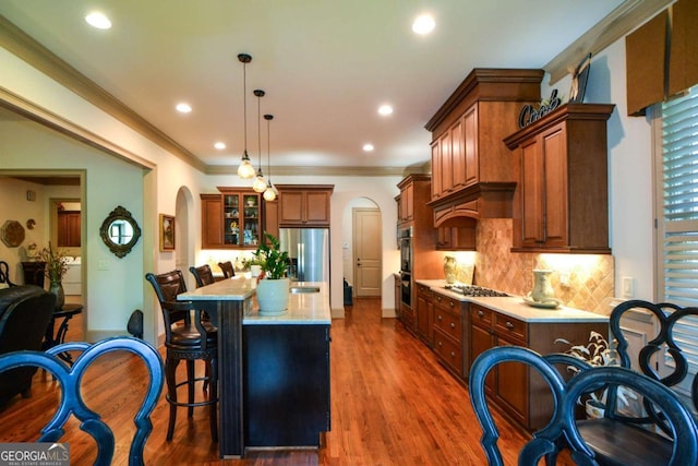 kitchen featuring appliances with stainless steel finishes, arched walkways, backsplash, and a breakfast bar area