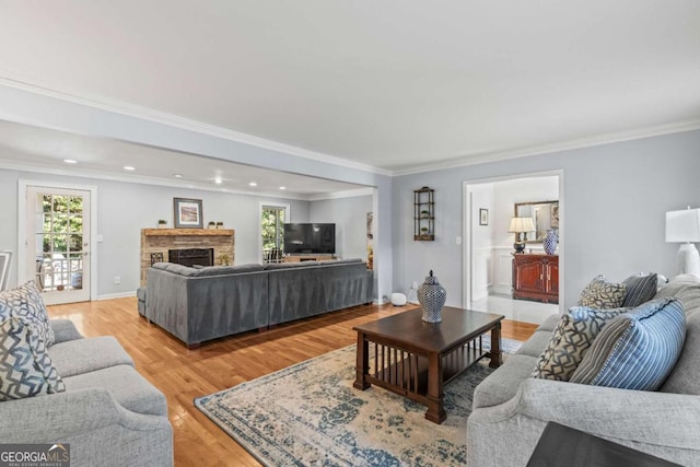 living room with light wood finished floors, baseboards, crown molding, a fireplace, and recessed lighting