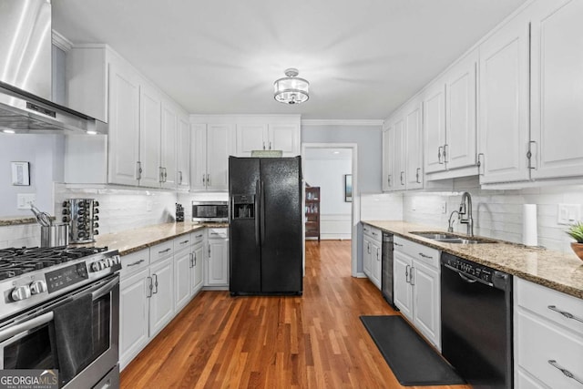 kitchen with black appliances, wall chimney exhaust hood, white cabinetry, and a sink