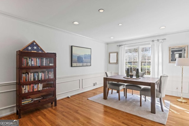 dining area with ornamental molding, recessed lighting, a wainscoted wall, and wood finished floors