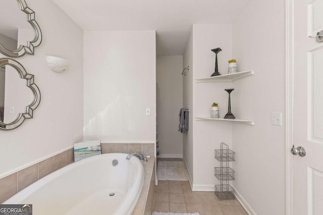 bathroom with baseboards, tiled tub, and tile patterned floors