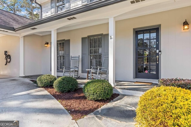 doorway to property with a porch, visible vents, and a shingled roof