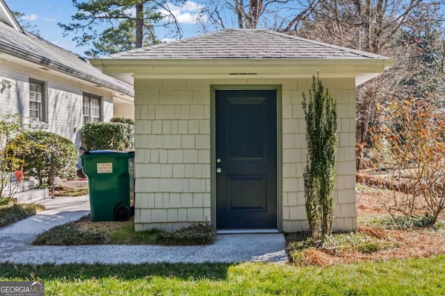 view of exterior entry with roof with shingles