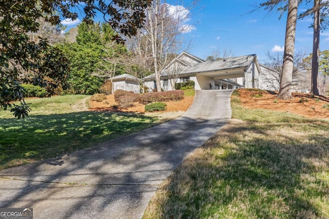 view of front of property with concrete driveway, an attached carport, and a front lawn