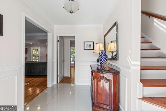 tiled entryway with a healthy amount of sunlight, wainscoting, and crown molding