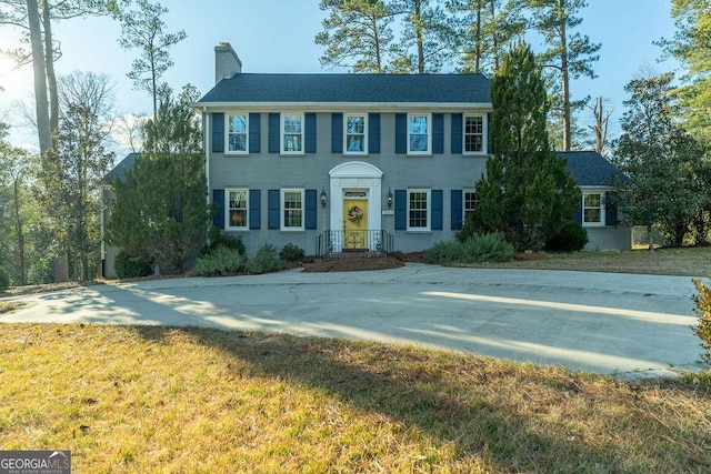 colonial house featuring a front yard and a chimney