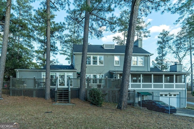 back of property featuring a deck, a chimney, fence, and a sunroom