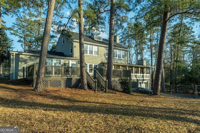 rear view of property with a sunroom, a chimney, stairs, fence, and a wooden deck