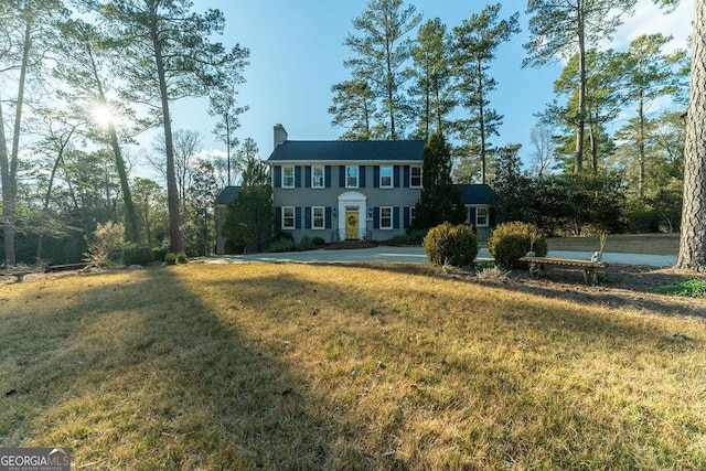 colonial-style house with a front lawn and a chimney