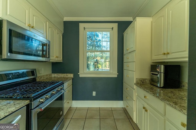 kitchen featuring light tile patterned floors, appliances with stainless steel finishes, light stone counters, and ornamental molding