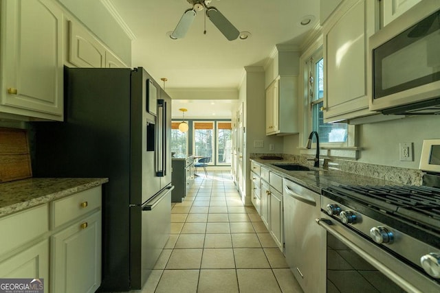 kitchen featuring appliances with stainless steel finishes, ornamental molding, a sink, and light tile patterned floors