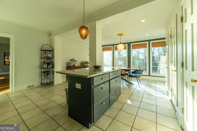 kitchen with light tile patterned floors, a center island, decorative light fixtures, and crown molding