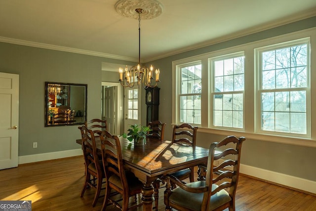 dining area with a chandelier, crown molding, baseboards, and wood finished floors