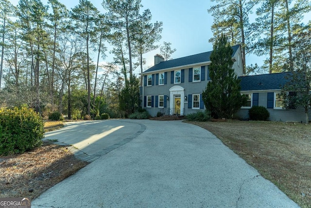 colonial house featuring driveway and a chimney