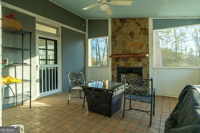 sunroom / solarium with a ceiling fan and a fireplace