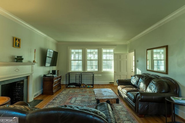 living area with a fireplace with flush hearth, crown molding, baseboards, and wood finished floors