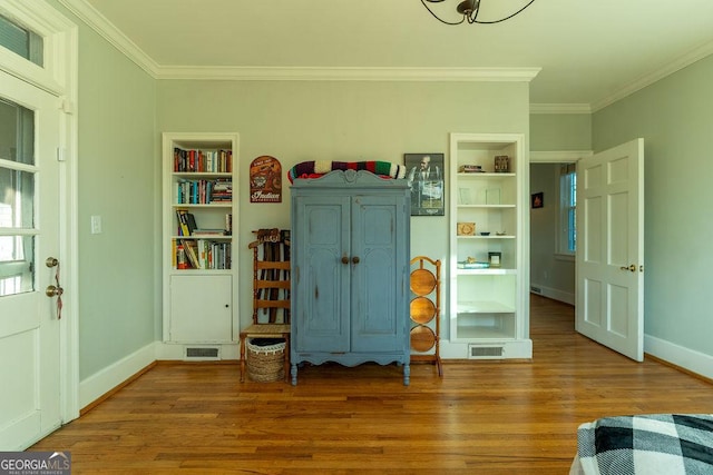 interior space with crown molding, wood finished floors, visible vents, and baseboards