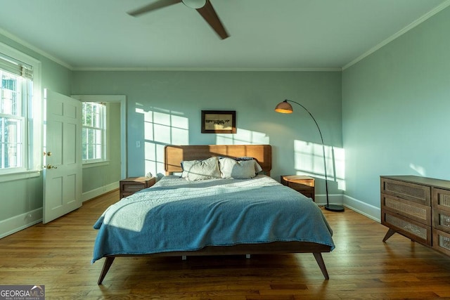 bedroom featuring baseboards, wood finished floors, a ceiling fan, and crown molding