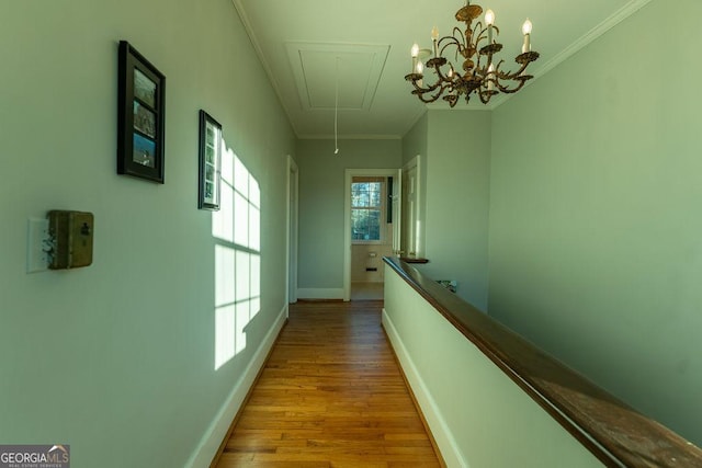 corridor with attic access, ornamental molding, baseboards, and wood finished floors