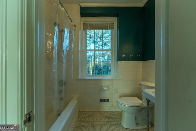 bathroom featuring a wainscoted wall, tile walls, toilet, shower / tub combo, and tile patterned floors