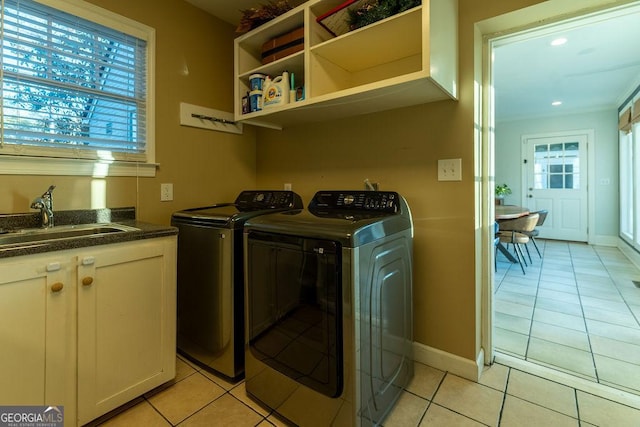 washroom with baseboards, separate washer and dryer, a sink, and light tile patterned flooring