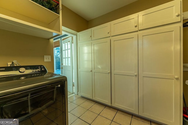 interior space with light tile patterned floors, washer / dryer, and white cabinetry