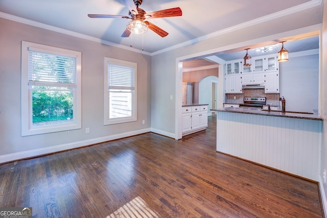 kitchen featuring arched walkways, electric stove, glass insert cabinets, and white cabinetry