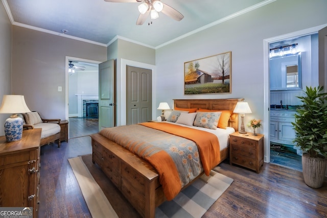 bedroom with connected bathroom, ornamental molding, wood finished floors, a fireplace, and a closet