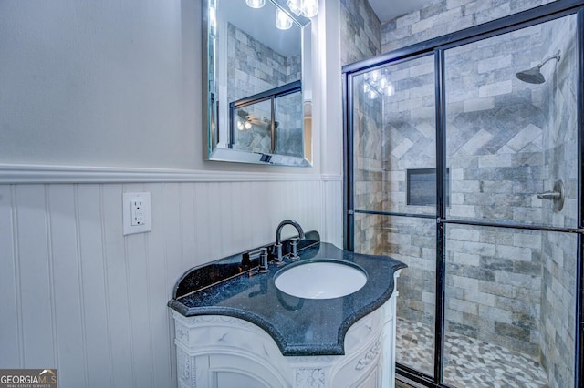 bathroom featuring a stall shower, vanity, and wainscoting