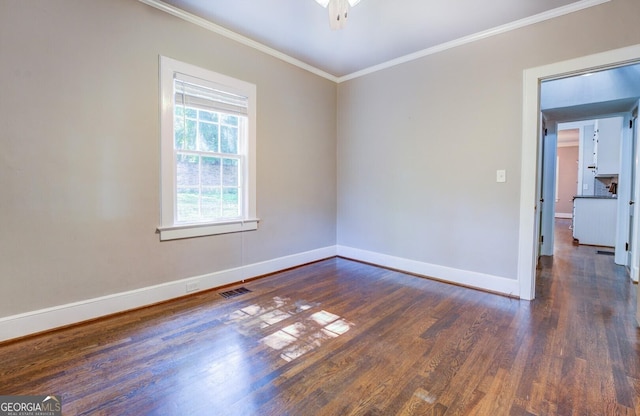 unfurnished room with visible vents, baseboards, dark wood finished floors, and crown molding