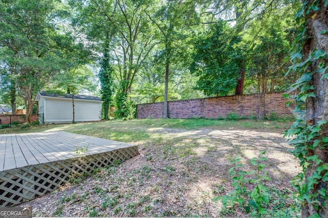 view of yard with a fenced backyard, a storage unit, an outbuilding, and a wooden deck