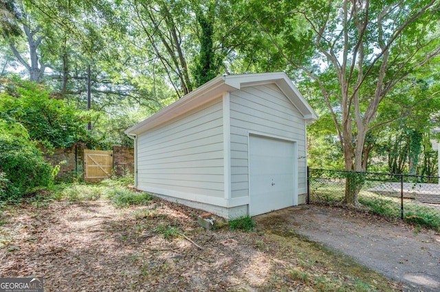 detached garage featuring a gate, driveway, and fence